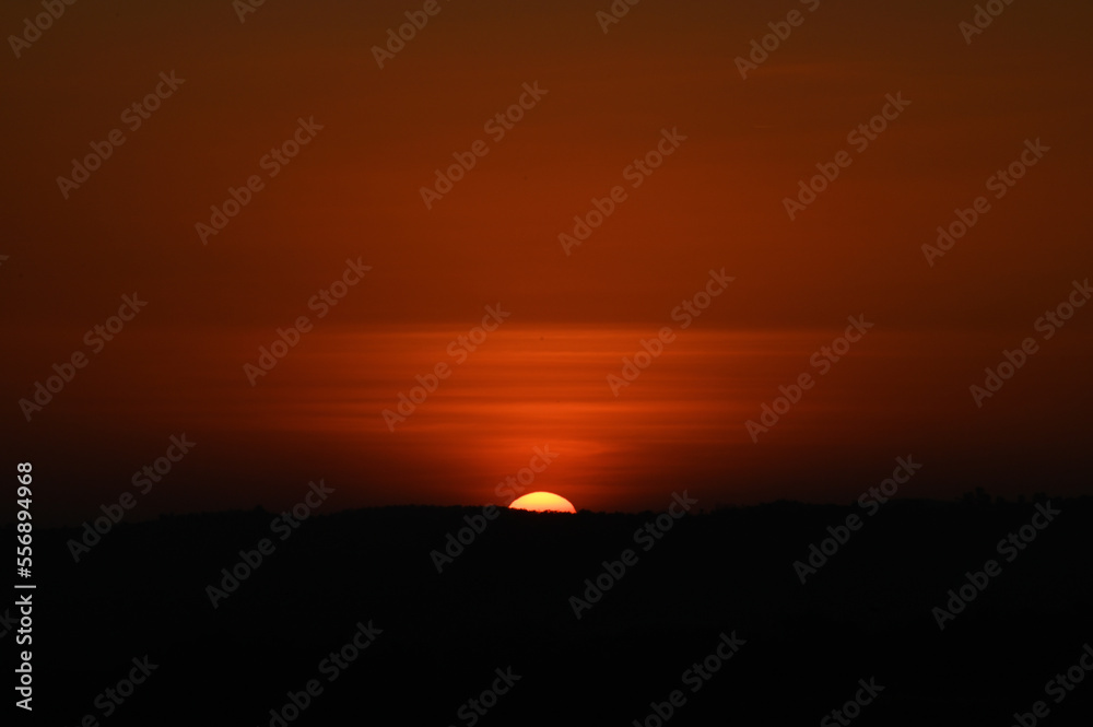 Silhouette image of a hill. Image of a Sunset behind the hill Silhouette image of a hill. Image of a Sunset behind the hill