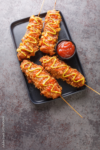 Canvas Print Korean corn dogs are made from sausage, mozzarella cheese on skewer and coat this in a sweet flour batter before rolling in a layer of toppings closeup on the plate