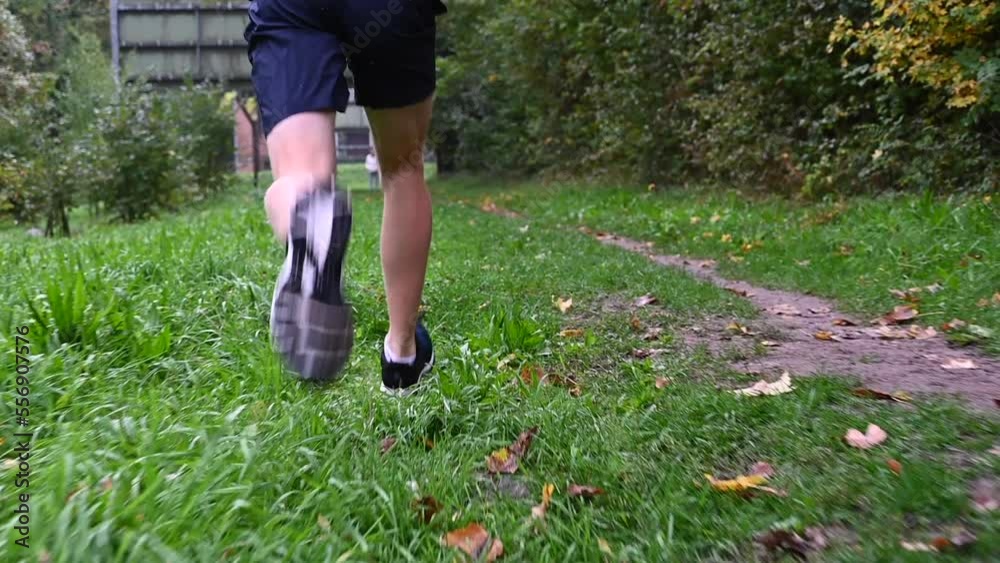 slow motion: a runner is on the grass and shows the underside of the sole with his long stride slow motion: a runner is on the grass and shows the underside of the sole with his long stride