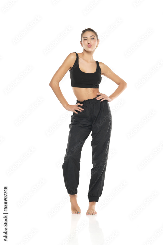 a young barefeet woman in black sweatpants and a tank top on a white background a young barefeet woman in black sweatpants and a tank top on a white background