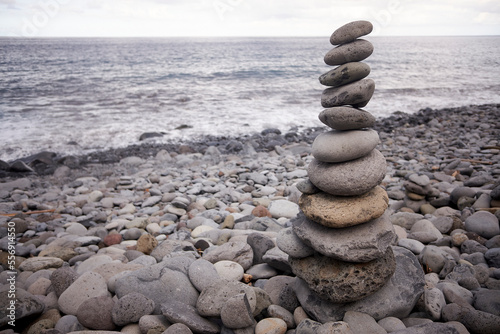 Tall balanced pile of pebble stones on a stony beach in Madeira, Portugal.