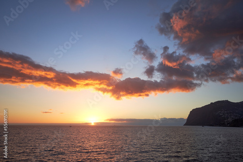 Beautiful sunset in Madeira, sun, clouds and sea. Summer holiday wallpaper.