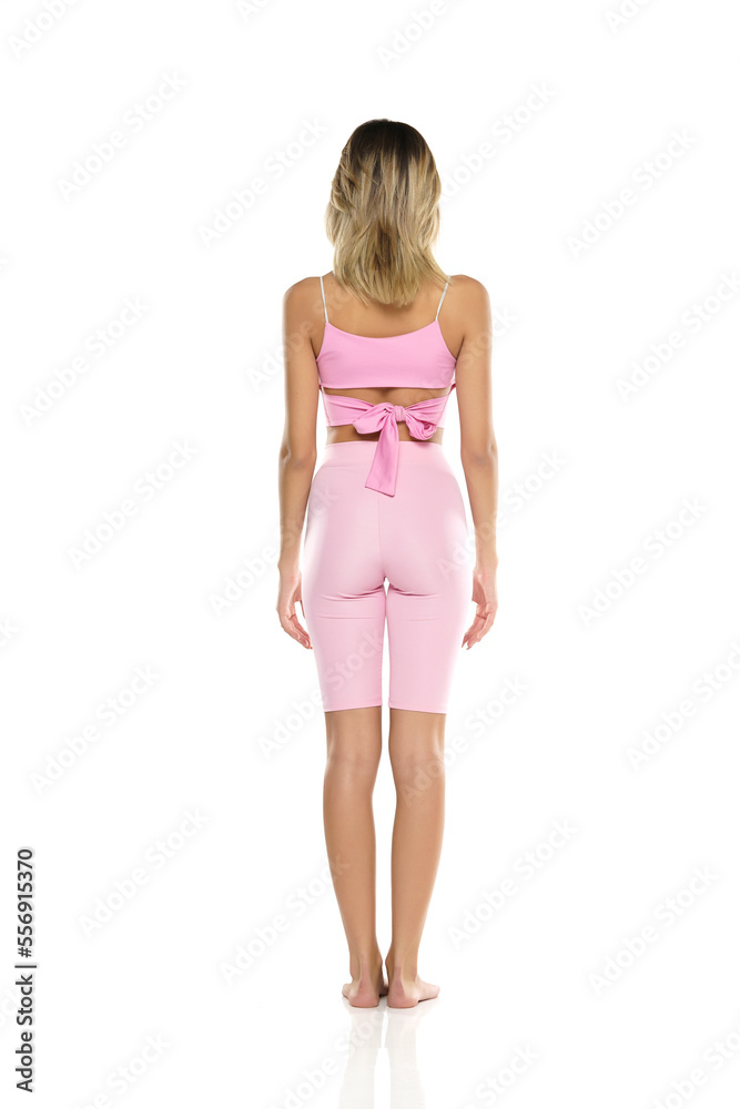 a young barefeet woman in pink short leggings and top posing on a white background. Back, Rear View a young barefeet woman in pink short leggings and top posing on a white background. Back, Rear View