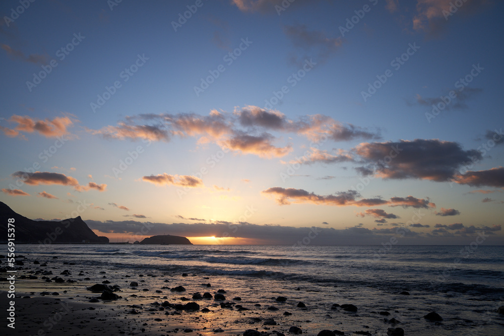 Sunrise landscape with sea, stones, clouds and blue sky in Porto Santo isle, near Madeira, Portugal.