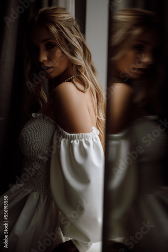 Close-up portrait of a girl standing near a mirror, hairdo and make-up