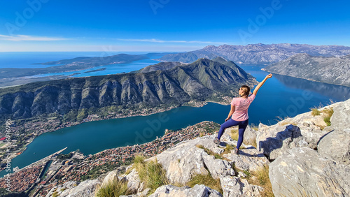 Woman with scenic view from Pestingrad (Derinski Vrh) of Kotor bay in sunny summer, Adriatic Mediterranean Sea, Montenegro, Balkan, Europe. Fjord winding along coastal towns. Lovcen, Orjen mountains