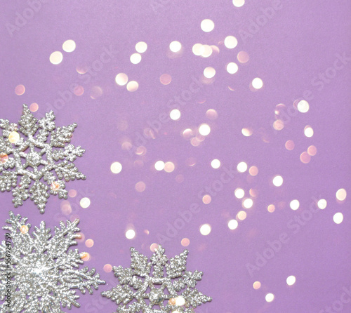 silver glittering snowflake ornaments on violet ground with bokeh effect and space for text