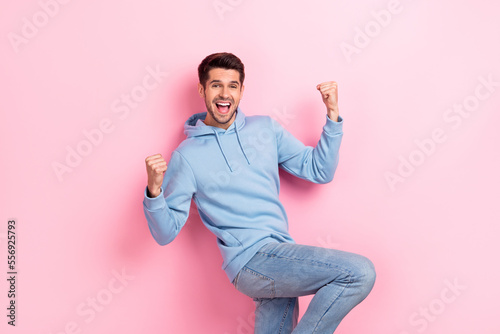 Fototapeta Photo of good mood lucky guy dressed blue sweatshirt rising fists shouting yelli