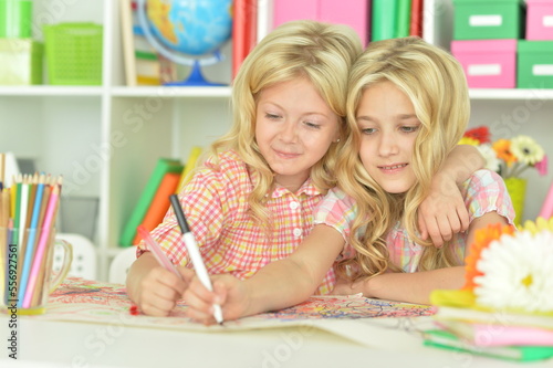 Two cute little girls drawing with pencils