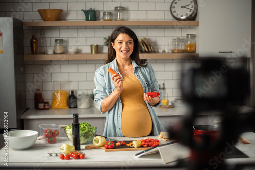 Beautiful pregnant woman preparing delicious food. Smiling woman preparing delicious food