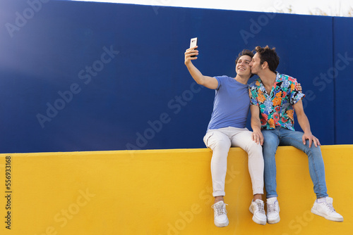 Happy young couple embraces. Two men taking selfie photo outside