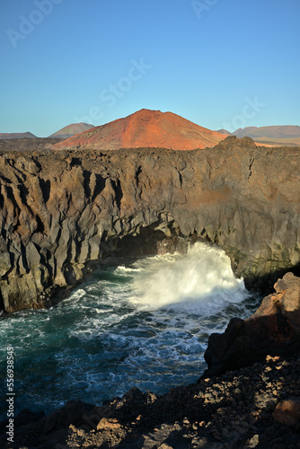 Die Sehenswürdigkeit Los Hervideros auf der Kanareninsel Lanzarote an der Küste mit Vulkanen im Abendrot