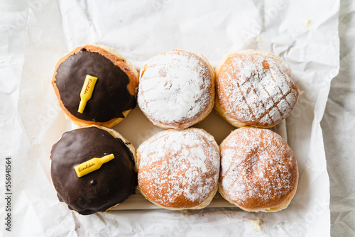 Assorted Krapfen, Berliner doughnuts or Pfannkuchen filled with jam or custard wrapped in white paper fresh from German bakery, traditional fried yeast dough pastry for New Years or carnival party