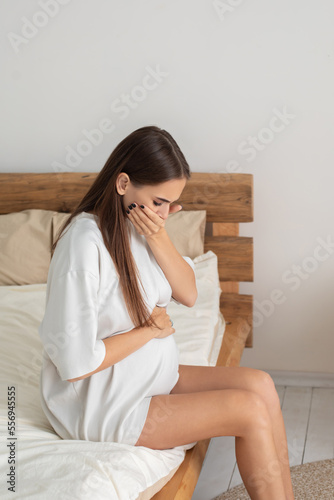Long-haired pregnant woman sitting on the bed © zinkevych