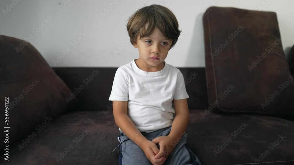One bored child sitting on couch at home with nothing to do. Young boy with pensive expression feeling boredom One bored child sitting on couch at home with nothing to do. Young boy with pensive expression feeling boredom