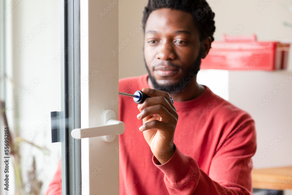 Young man repairing window with screwdriver at home Young man repairing window with screwdriver at home