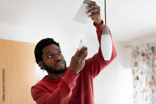 Young man changing bulb in electric light photo