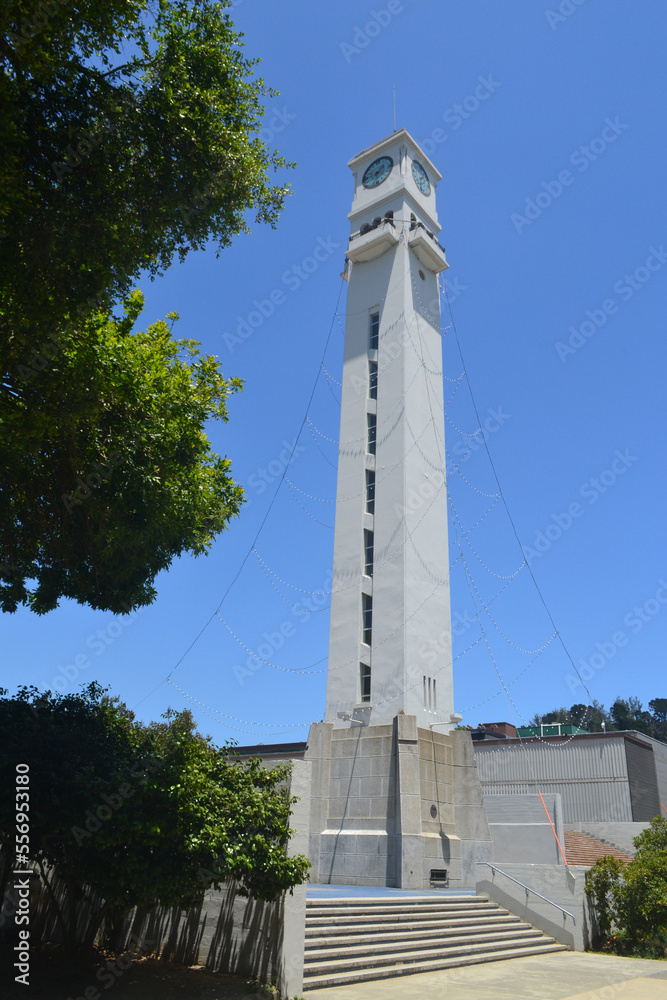 the clock tower at the university of concepcion in chile with some beautiful gardens