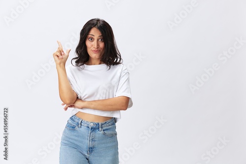 Woman in white t-shirt on white background brunette hands up gestures and signals poses in jeans emotion, lifestyle smiles, copy space