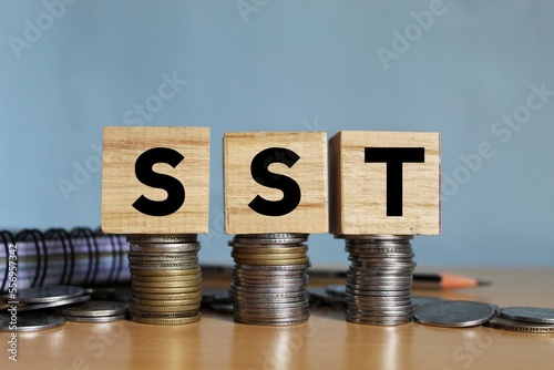 SST. Sales and Service Tax on wooden block on stacked coins