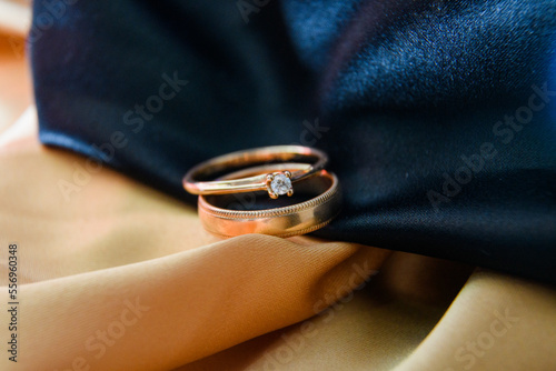 Wedding rings in gold and black satin fabric. Engagement. wedding photography. Gold paired rings crossed. Volumetric photography. Wedding. An offer of marriage. Diamond