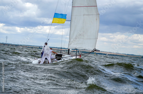 Flag of Ukraine on a sailing yacht on the waves in stormy weather