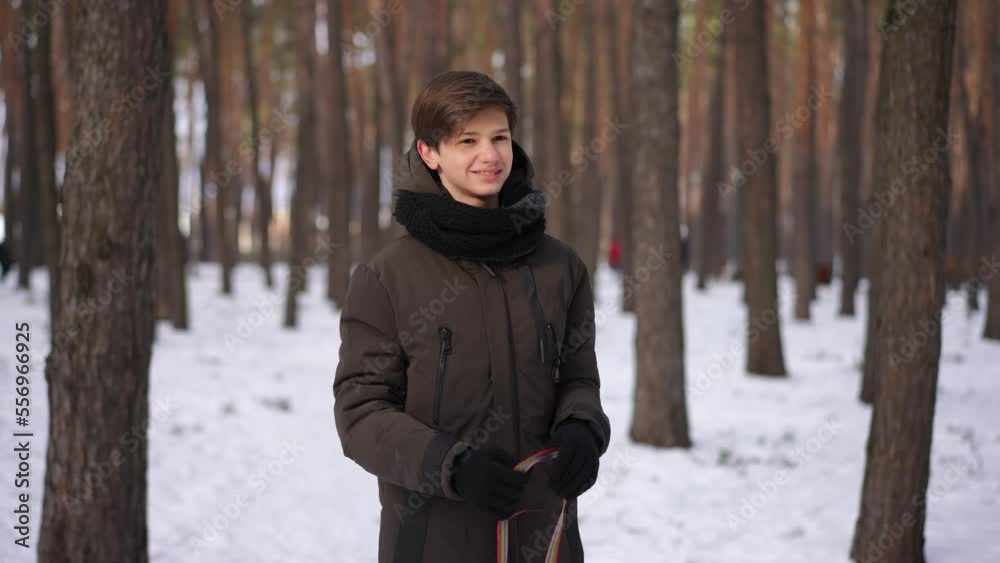 Zoom in portrait of smiling teenage Caucasian boy looking away standing in winter park turning in slow motion. Happy confident handsome teenager enjoying weekend leisure in forest Zoom in portrait of smiling teenage Caucasian boy looking away standing in winter park turning in slow motion. Happy confident handsome teenager enjoying weekend leisure in forest