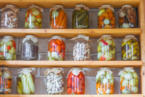 Pickled vegetables, dry coffee, bottle caps in glass jars on storage shelves.