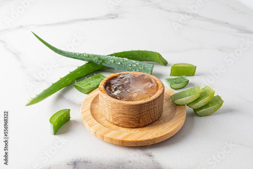 aloe vera gel in a wooden bowl on a marble background with leaves and slices of fresh aloe. the concept of skin care of the face, body, hair.
