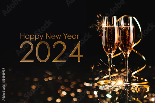 Obraz na płótnie Happy New Year 2024! Two glasses with champagne, ash and serpentine bokeh on a dark background w salonie