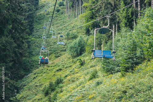 Cable car, ski lift with blue seats in summer among the green pine trees