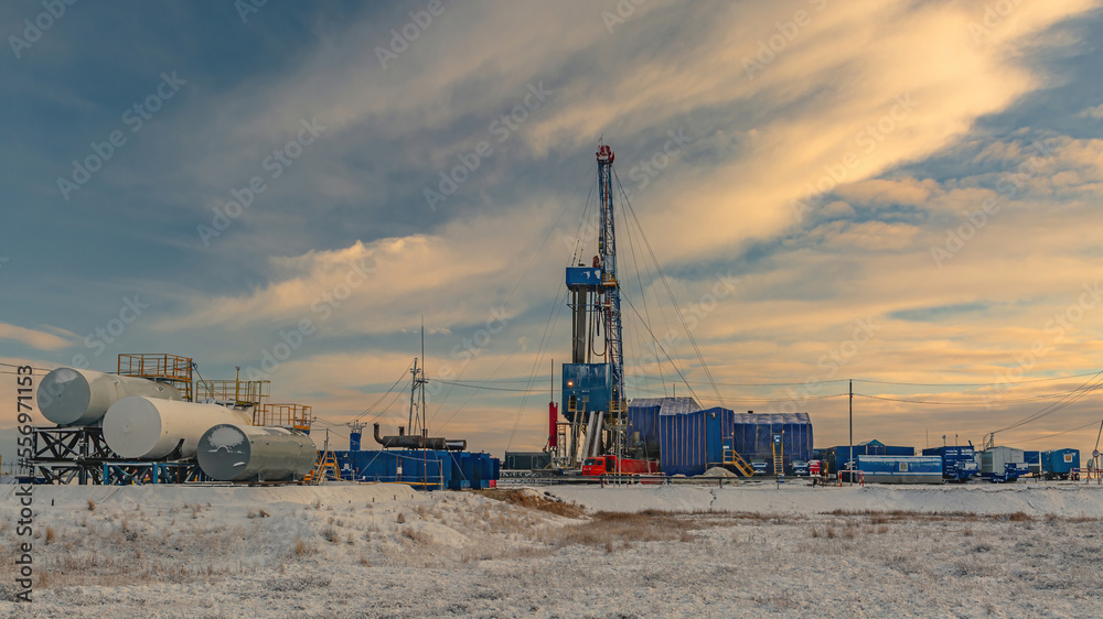 Drilling wells at an oil and gas field in the Far North. Industrial infrastructure and drilling rig. Beautiful winter sky. Polar Day
