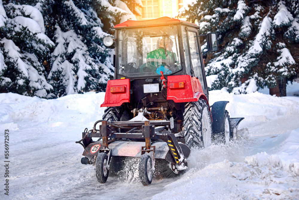 Tractor cleaning snow in city park after blizzard. Tractor is sweeping
