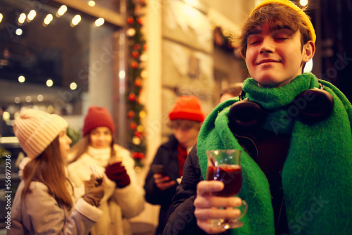 Emotional young people, friends meeting, smiling, drinking hot drinks at evening city street at winter time. Emotions, love, friendships, ad, sales concept