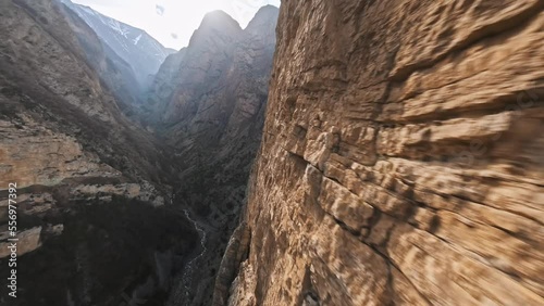 FPV sports drone dive shot mountain rock geology formation stone structure speed falling over creek stream canyon sunny nature aerial view. Cliff terrain cinematic altitude desert valley landscape 4k