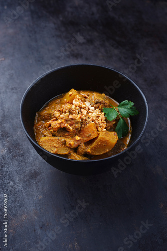 Traditional Indian vegetarian Madras curry stew with sweet potatoes and roasted cashew nuts served as close-up in design bowl with copy space