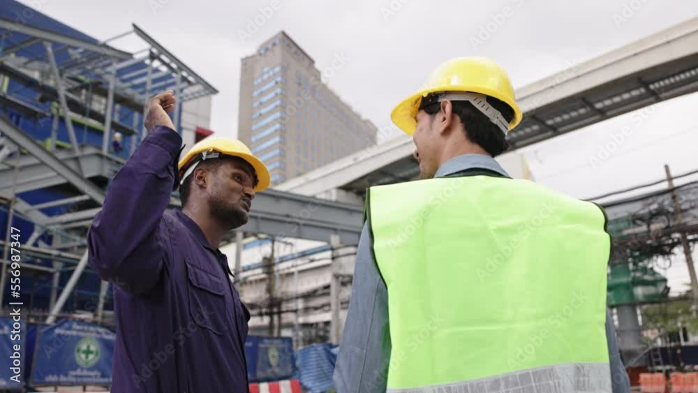 Structural engineers and construction workers are holding blueprints inspecting structure. sky train track construction in city. Blue collar wears a safety hardhat while working on construction site. Structural engineers and construction workers are holding blueprints inspecting structure. sky train track construction in city. Blue collar wears a safety hardhat while working on construction site.