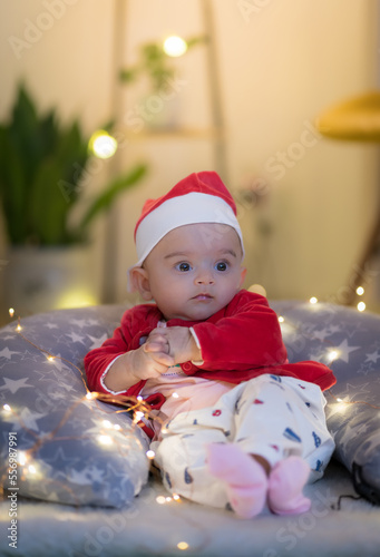 Baby wearing a santa cap and robe posing on a pillow 