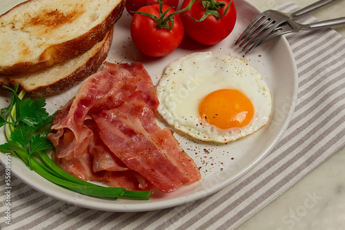 Breakfast  fried egg  bacon and bread  with cherry  on a light background  homemade  no people 