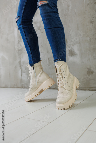 Female legs in jeans and white leather boots made of natural leather. A collection of women's spring modern shoes
