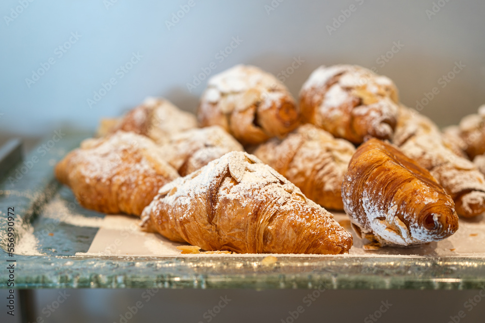 Group of baked croissant with sugar icing topping in the glass plate, serving in the breakfast buffet line. Food object photo.