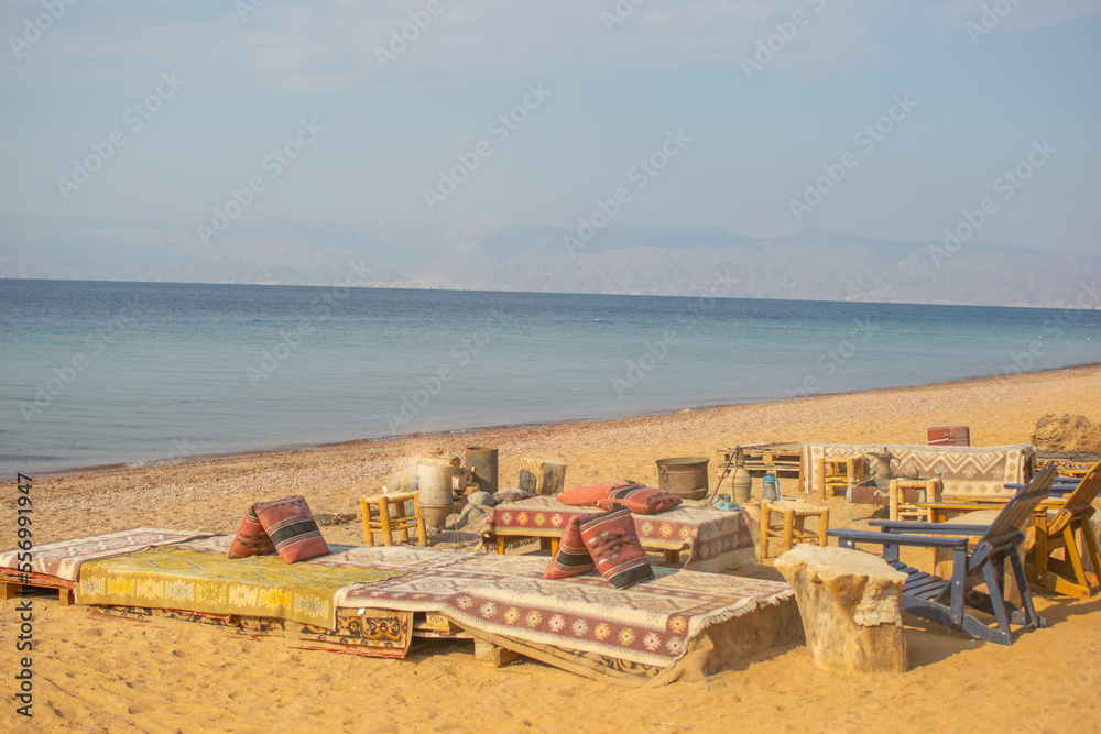 Traditional Authentic Colorful Bedouin Camp on the beach  with coffee pots and fire place, jars, cauldrons, on the sand at the Red Sea near Aqaba, Jordan, exotic relaxing travel tourism concept 