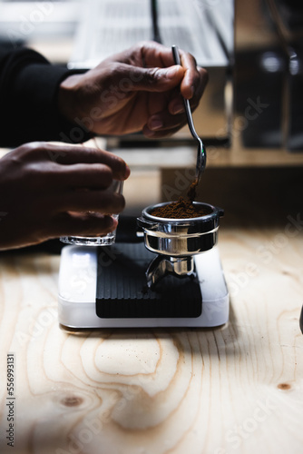 Hands of a black young man making coffee with an espresso machine