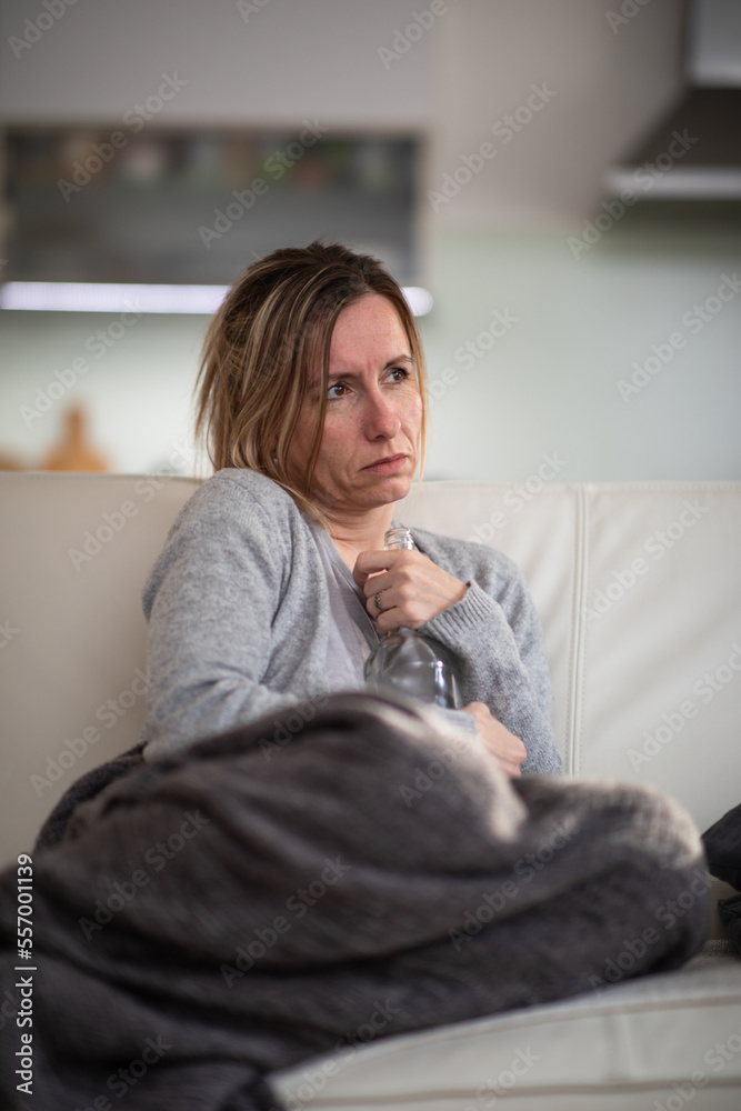 Midlle aged woman at home with a bottle of strong alcohol in her hands Midlle aged woman at home with a bottle of strong alcohol in her hands
