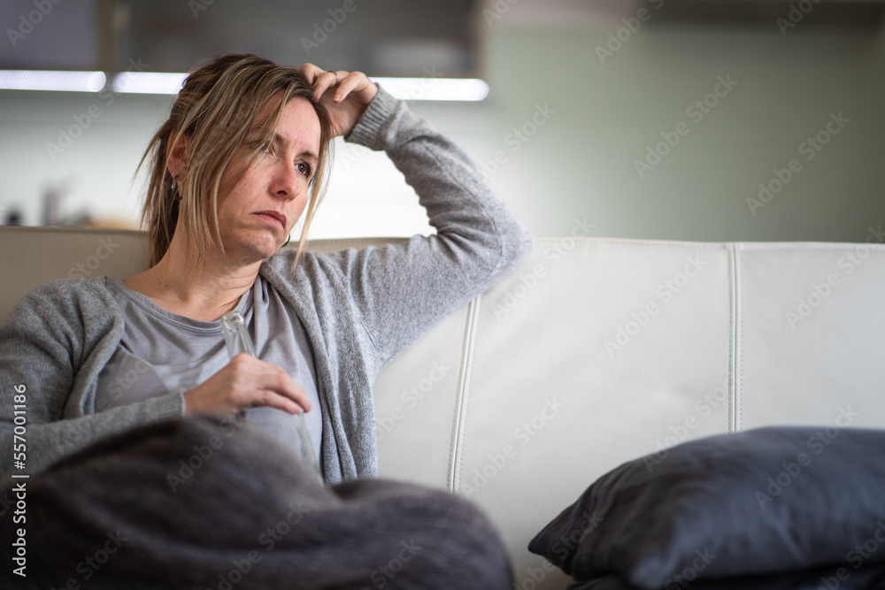 Midlle aged woman at home with a bottle of strong alcohol in her hands Midlle aged woman at home with a bottle of strong alcohol in her hands