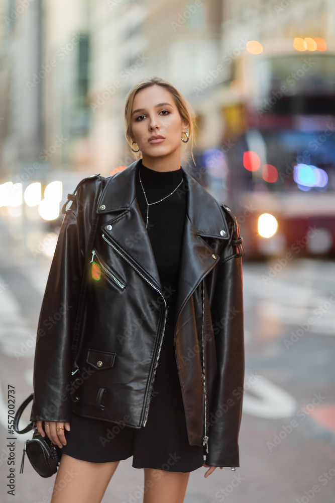 Obraz premium woman in stylish black outfit standing near blurred cars on street in New York city