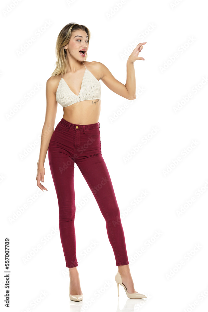 Smiling Woman In Burgundy Jeans And Top Presenting Something On her Empty Palm On A White Background Smiling Woman In Burgundy Jeans And Top Presenting Something On her Empty Palm On A White Background