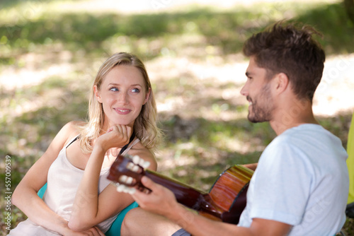 young lovers under the shade of trees playing guitar