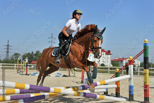 Girl riding a horse on jumping competitions.