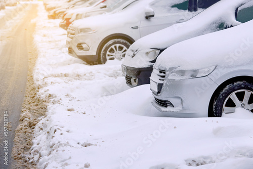 Cars covered in snow parked in row on parking lot in winter seson, parked cars covered with snow after snow storm.